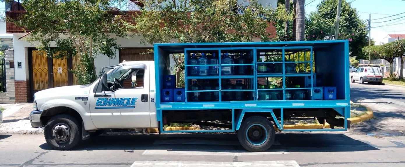 Camión de reparto de Embotelladora Echanique cargado con bidones y cajones de soda en una calle de Villa Martelli